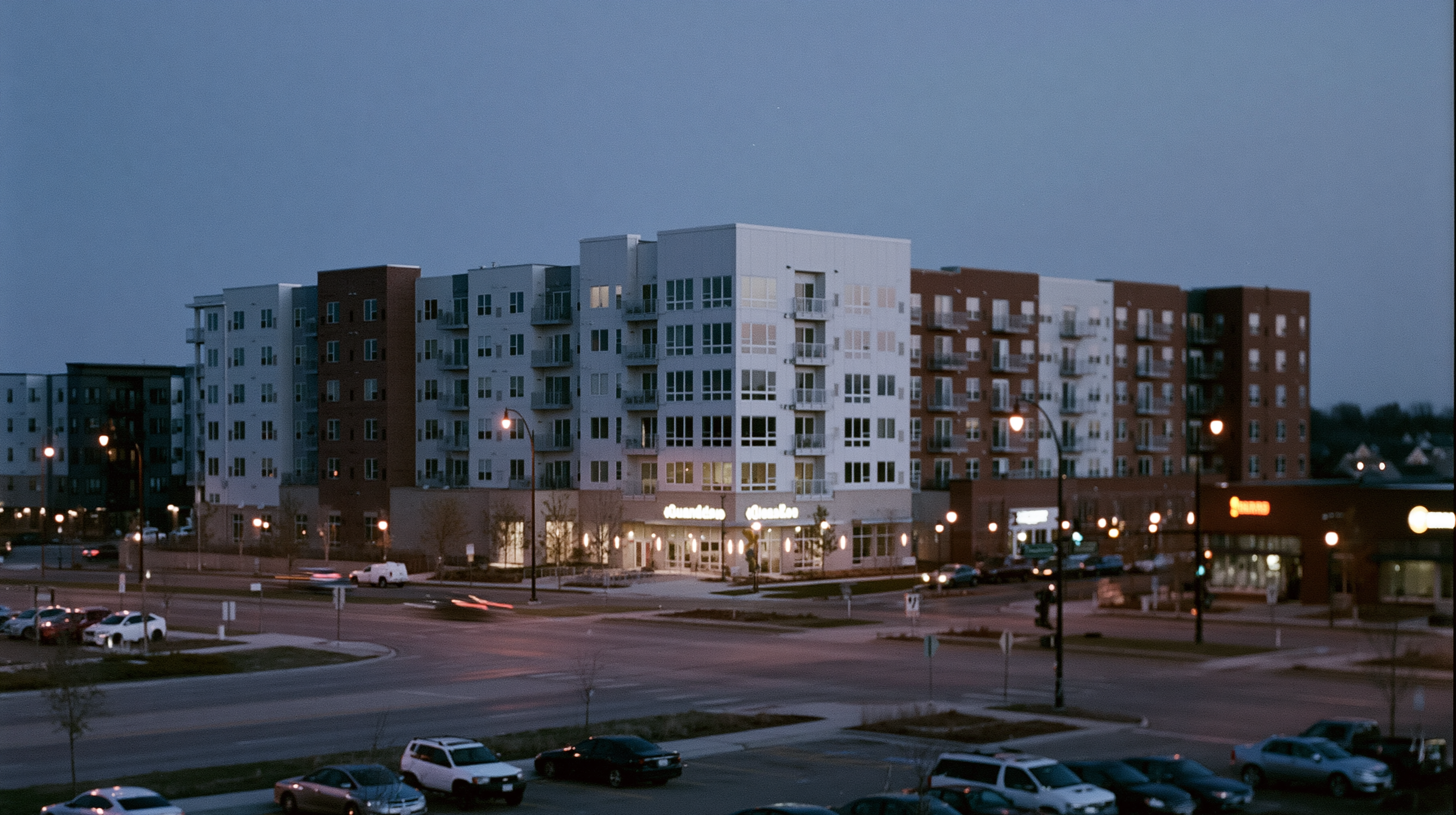 A mid-rise wood-frame multifamily apartment building at dusk